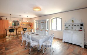 A spacious kitchen with a dining area, featuring a marble countertop, white cabinetry, and a variety of kitchen utensils. - Stunning home in Robion (Robion)