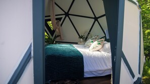 Un lit doté d’une tête de lit à motifs géométriques, d’un plaid turquoise et de deux coussins ornés de motifs de feuilles.