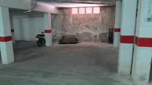 A parking garage with concrete pillars, a motorcycle, and a covered vehicle. - O-1 Beautiful ground floor close to the beach and with pool (Calella de Palafrugell)