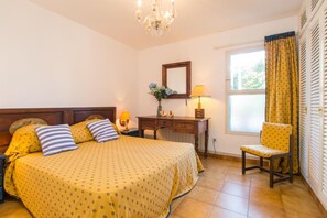 A hotel room with a bed, a desk, a chair, a window with curtains, and a chandelier. - O-1 Beautiful ground floor close to the beach and with pool (Calella de Palafrugell)