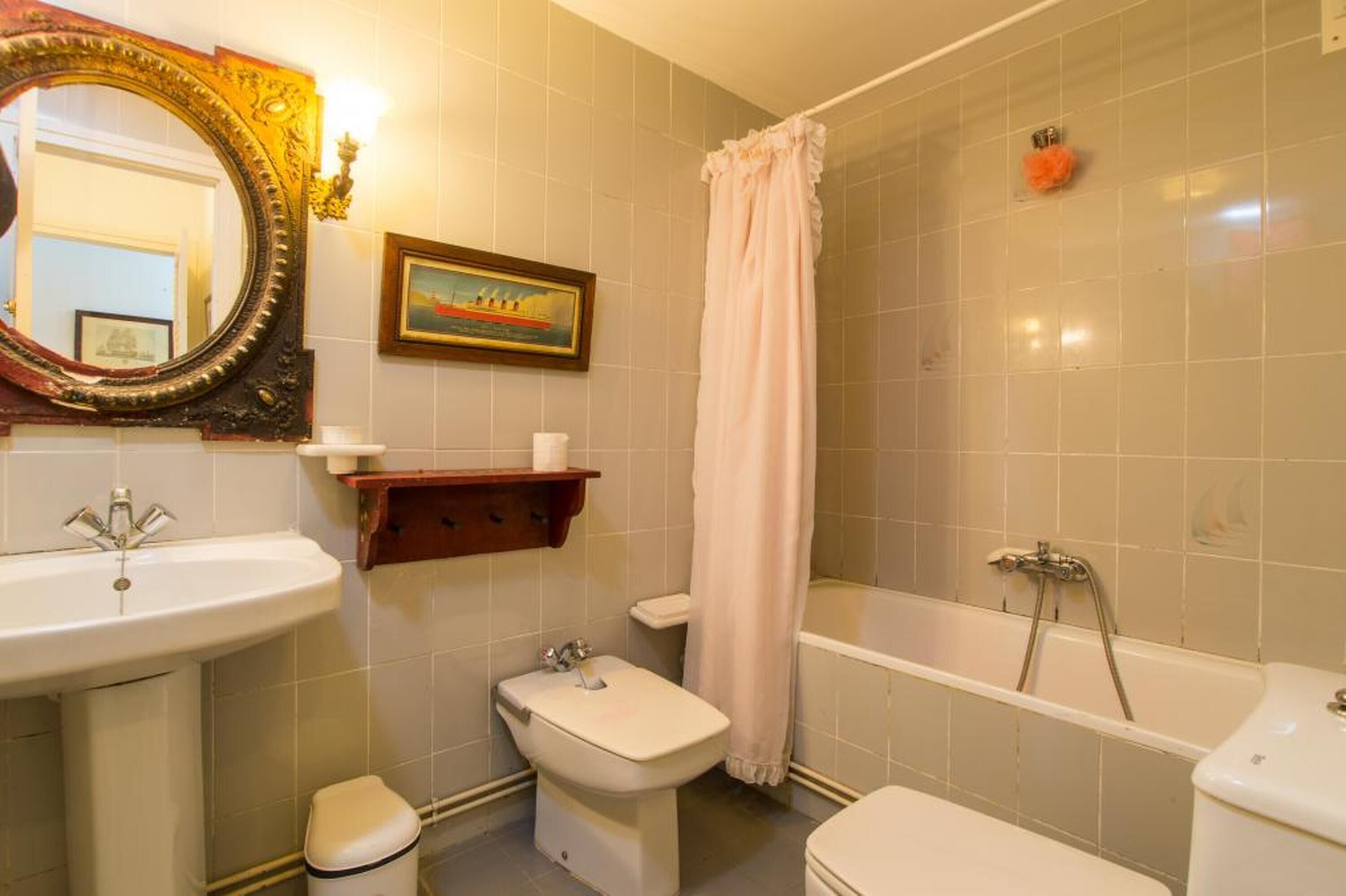 Un baño con bañera, dos lavamanos, inodoro, cortina de ducha y un cuadro en la pared.