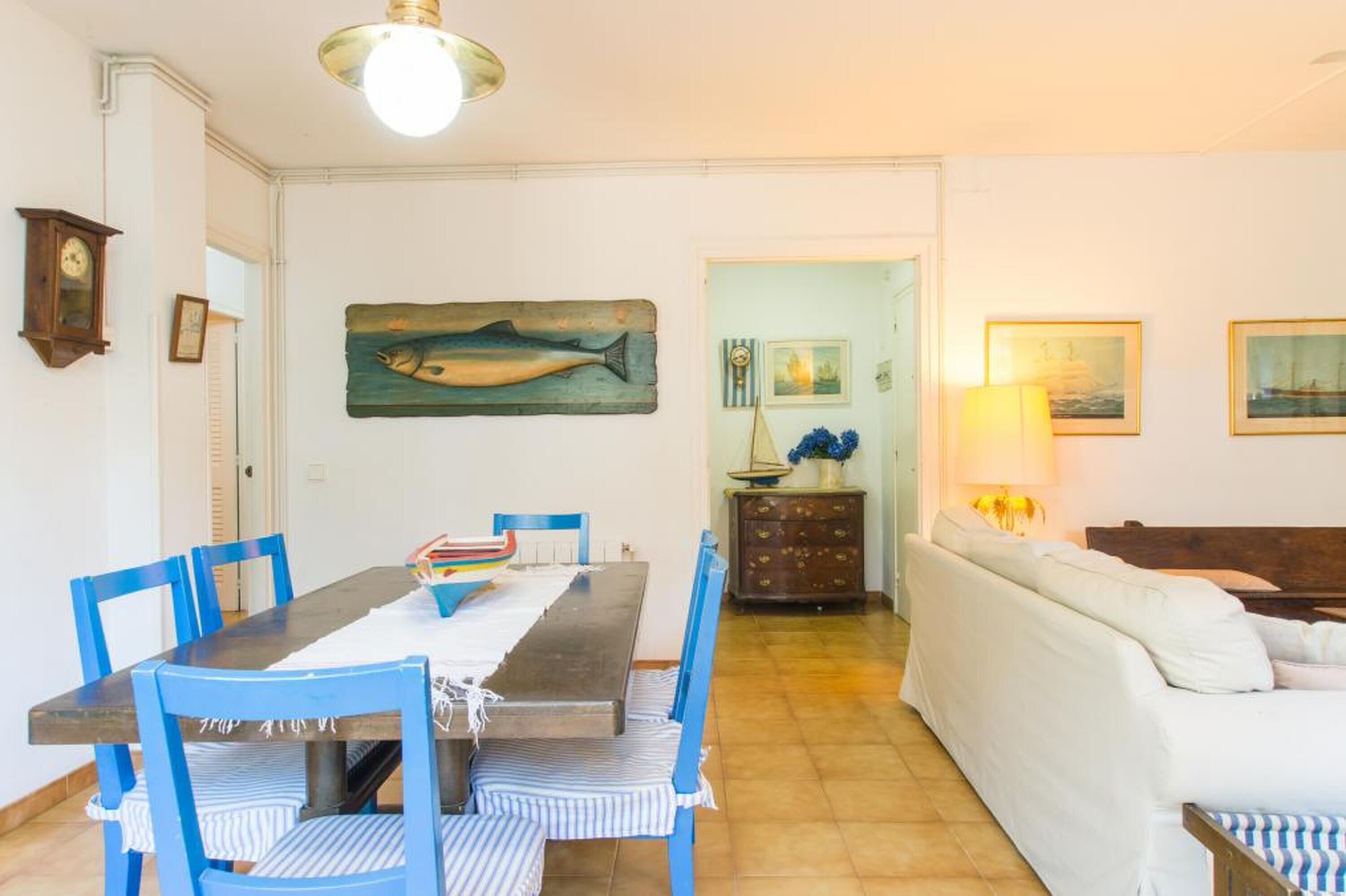 A dining area with a table, chairs, and a painting of a fish on the wall.