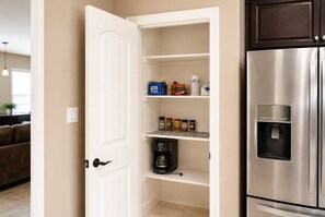 A kitchen with a built-in pantry, a stainless steel refrigerator, and a coffee maker on the countertop.