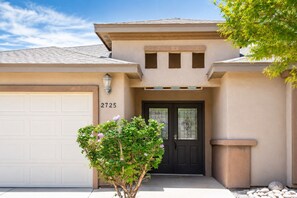 A residential house with a garage, a front door, and a small tree in front.