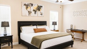 A bedroom with a bed, two nightstands, a desk, and a world map artwork on the wall.