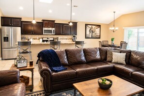 A modern kitchen with dark wood cabinets, stainless steel appliances, and pendant lighting.