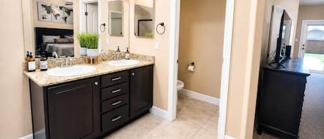 A modern bathroom with two sinks, dark cabinetry, and a large mirror.