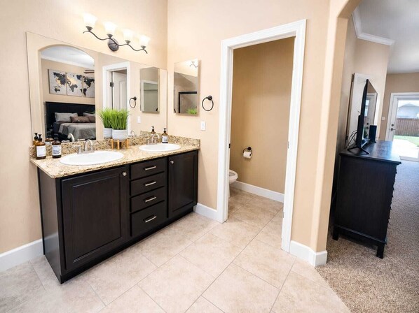 A modern bathroom with two sinks, dark cabinetry, and a large mirror.