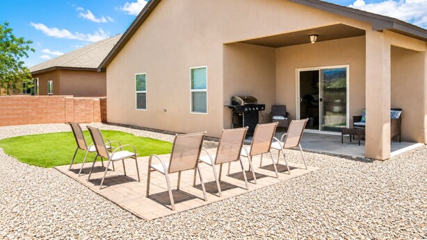 A house with a patio area, outdoor seating, and a barbecue grill.