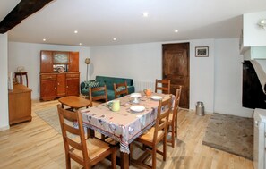 A dining area with a table set for four, surrounded by wooden chairs, a green sofa, and a wooden cabinet. - Amazing home in Saint-Alban-d'Ay with WiFi (Saint-Alban-d'Ay)