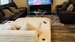 Una sala de estar con una televisión de pantalla plana, dos sofás, una mesa de centro y una alfombra mullida.