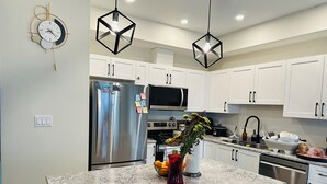 Una cocina moderna con armarios blancos, electrodomésticos de acero inoxidable y encimera de granito.