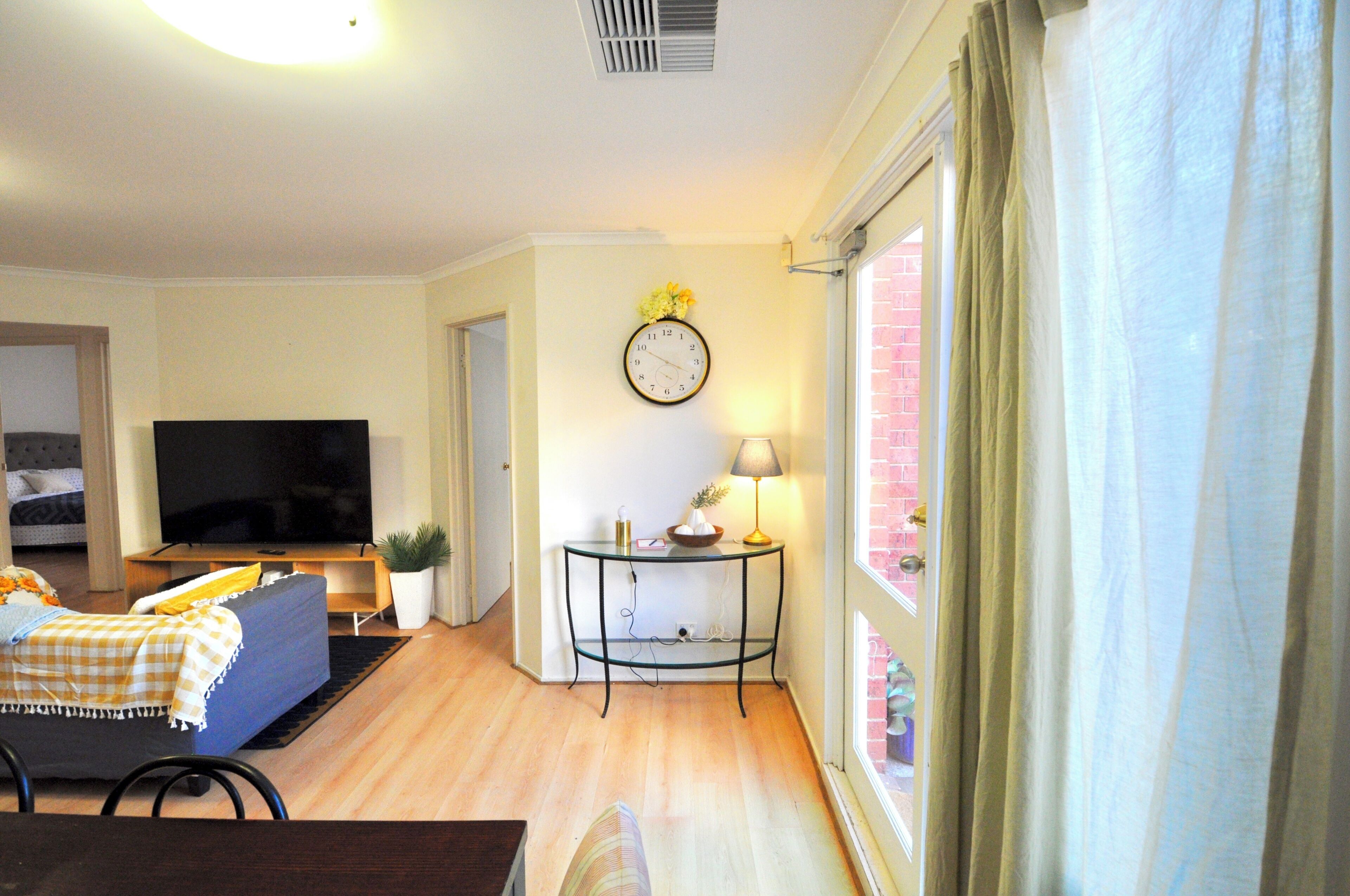 A living room with a television, sofa, and a table with a lamp.