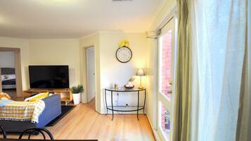 A living room with a television, sofa, and a table with a lamp.