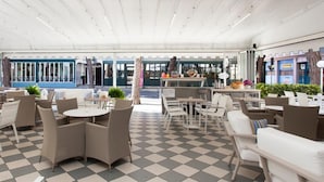 A cafe with outdoor seating, a checkered floor, and a view of the street. - Hotel Riviera (Jesolo)