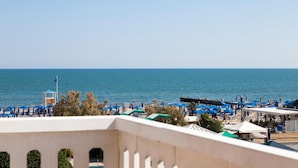 A beach with blue umbrellas and a lifeguard tower. - Hotel Riviera (Jesolo)