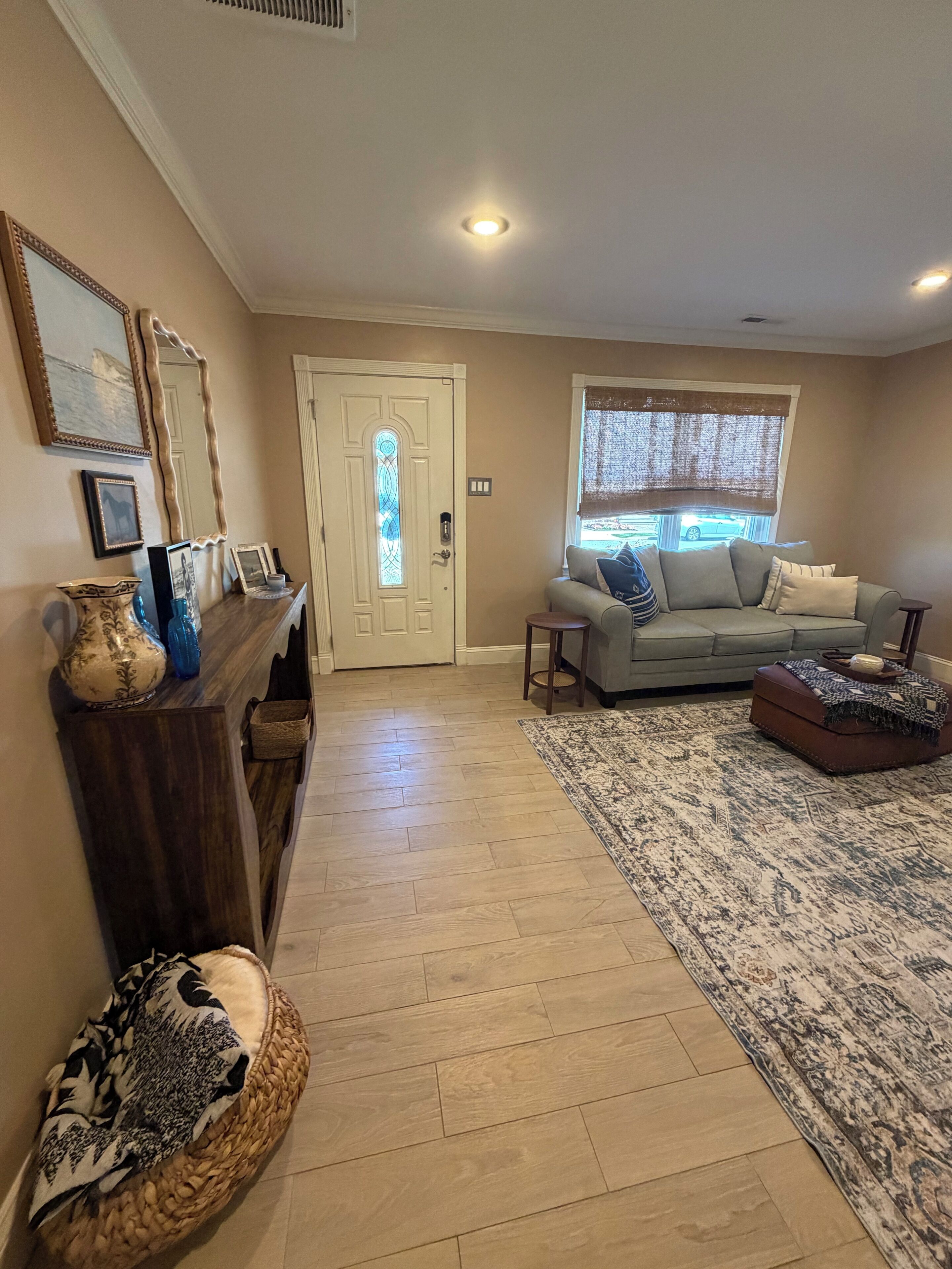 A living room with a sofa, a coffee table, a rug, and a door with a stained glass window.