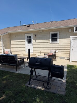 A patio with a grill, outdoor furniture, and a house with a door and windows. - Coastal Escape - Backyard Oasis & Beach Vibes with Kayaks and Fitness Center (Ventnor City)