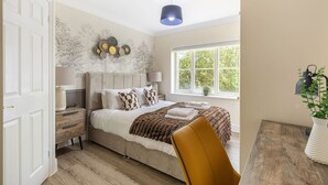 Un dormitorio con cama, mesitas de noche, una ventana con vistas y una lámpara colgante.