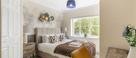 A bedroom with a bed, bedside tables, a window with a view, and a hanging lamp.