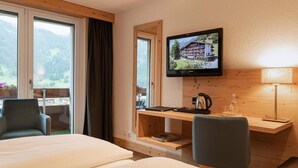 Una habitación de hotel con cama, escritorio, televisor y vistas al exterior.