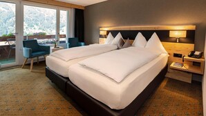 Una cama doble con cabecera de madera, una mesita de noche con lámpara y una silla.