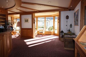 A room with a wooden interior, a large window, a seating area, and a view of the outside. - Hotel Restaurant Alpina (Grindelwald)