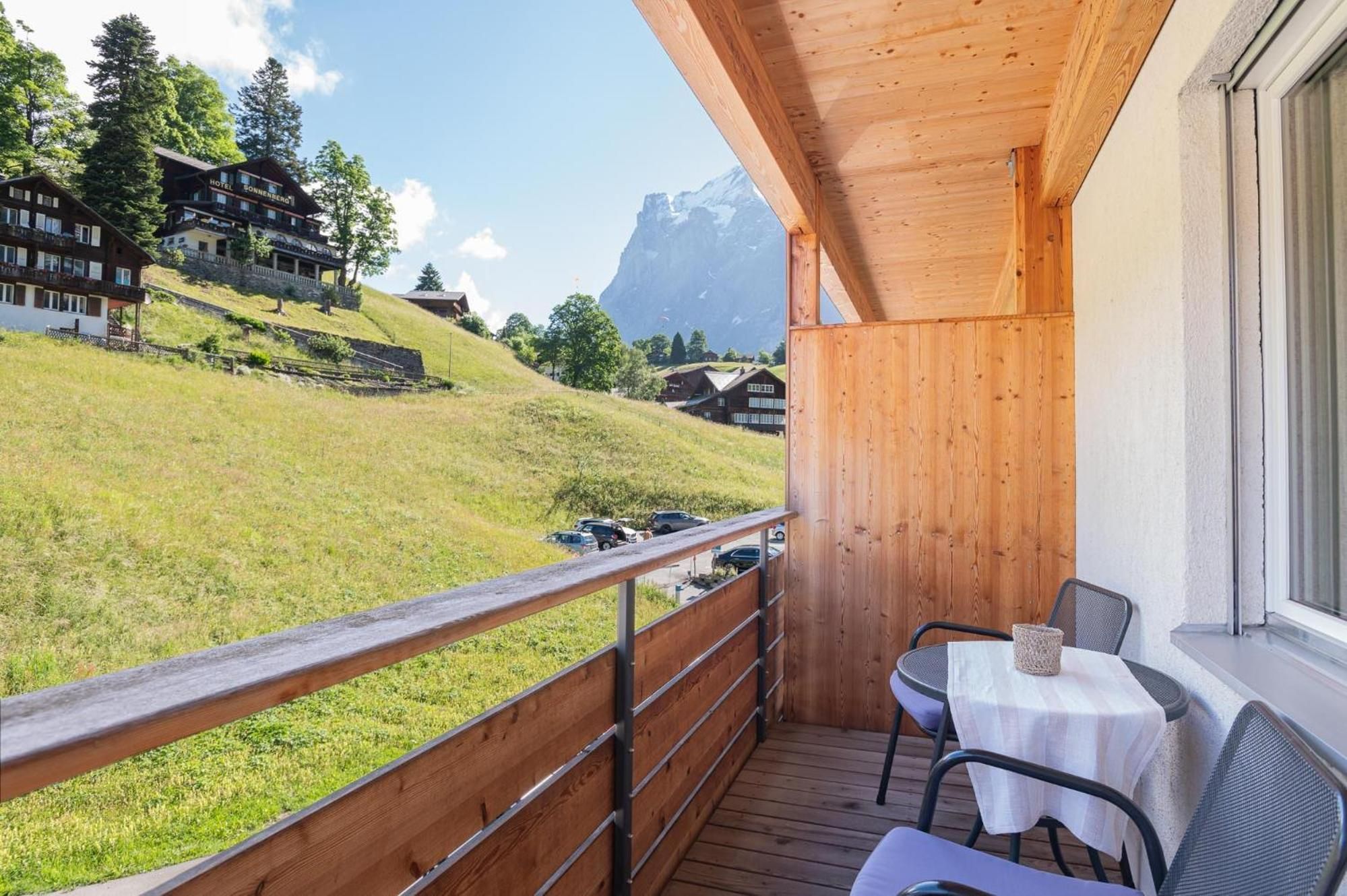 Un balcón de madera con vistas a una montaña y un hotel al fondo.