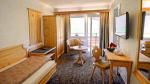 Una habitación de hotel con cama, escritorio, silla, televisión y vistas al exterior.