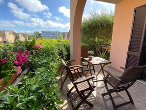 A covered outdoor patio with a table and chairs, surrounded by lush greenery and flowering plants. - B&b L'ulivo Fiumicino (Fiumicino)