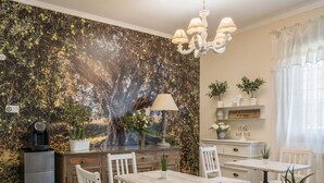 A dining area with white chairs and tables, a chandelier, and a wall mural. - B&b L'ulivo Fiumicino (Fiumicino)