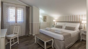 A bedroom with a bed, bedside tables, a chair, a bench, and a window with curtains. - B&b L'ulivo Fiumicino (Fiumicino)