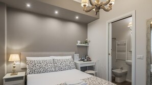 A bedroom with a bed, bedside table, lamp, and a desk with a chair. - B&b L'ulivo Fiumicino (Fiumicino)
