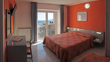 A hotel room with a bed, a desk, and a balcony with a view.