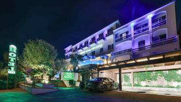 A multi-story hotel with a modern design, featuring balconies and a covered parking area.