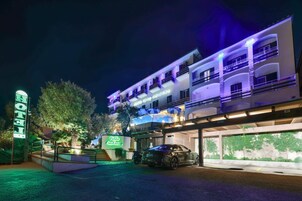 A multi-story hotel with a modern design, featuring balconies and a covered parking area.