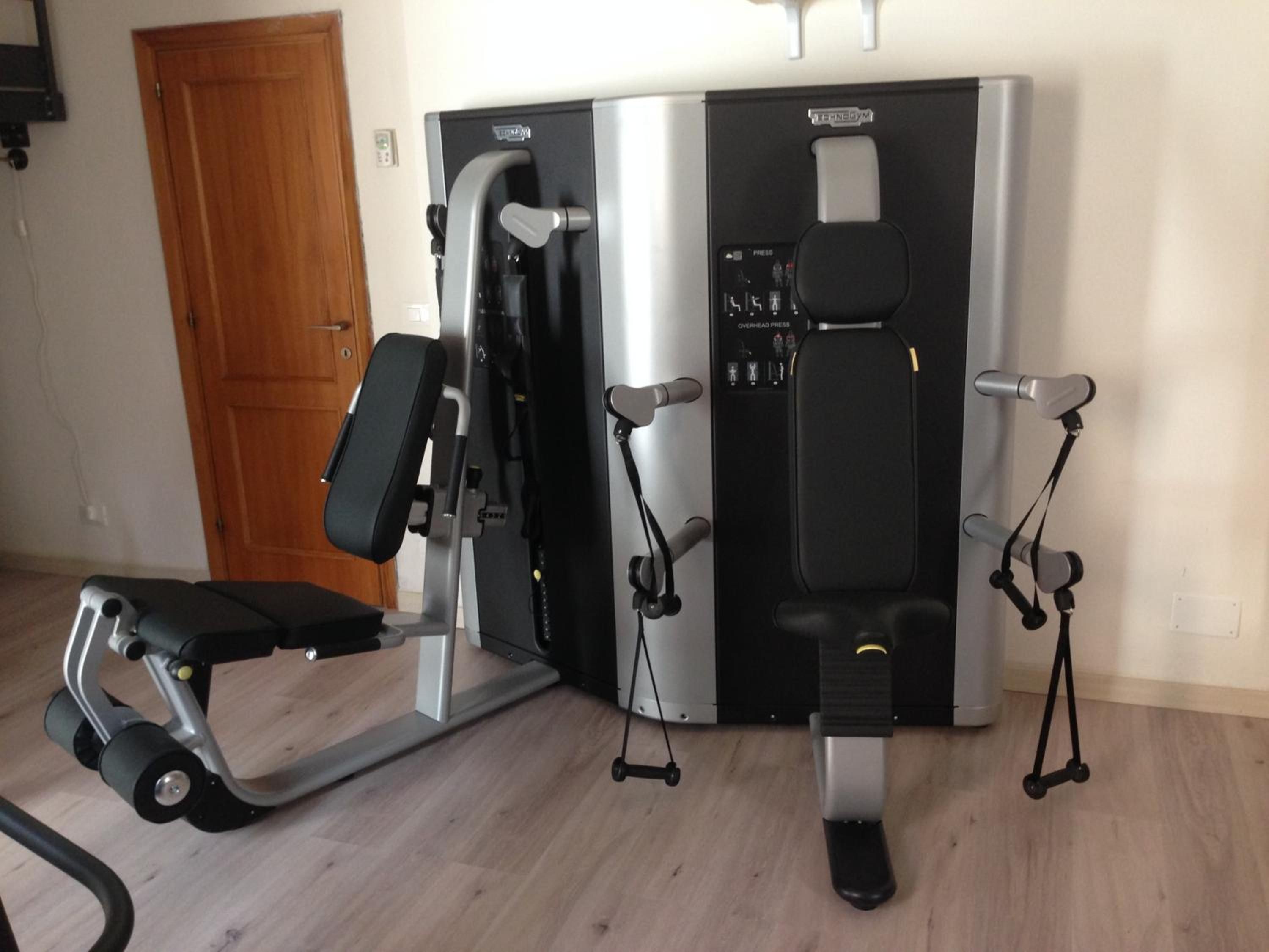 Una palestra in casa con una panca per pesi, una macchina per lo sviluppo del petto e una sbarra per trazioni.