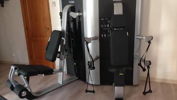Una palestra in casa con una panca per pesi, una macchina per lo sviluppo del petto e una sbarra per trazioni.