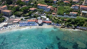 An aerial view of a coastal town with a beach, buildings, and clear blue waters. - Hotel Villa Ombrosa (Portoferraio)