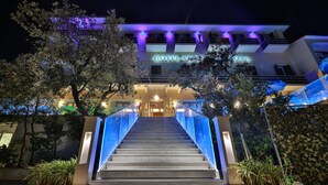 A hotel entrance with a staircase leading up to the main entrance, surrounded by trees and illuminated by blue lighting. - Hotel Villa Ombrosa (Portoferraio)