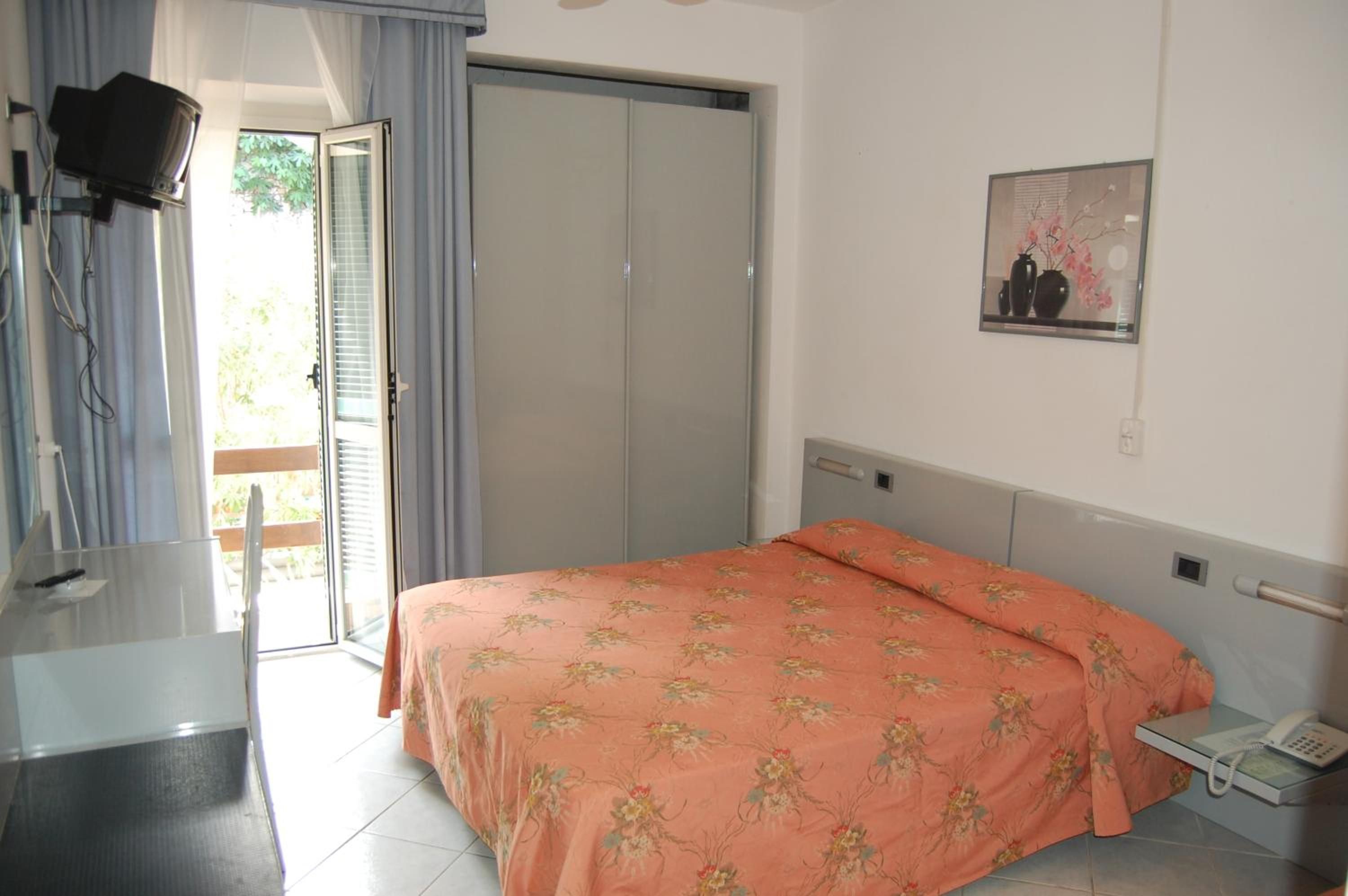 Una camera da letto con un letto, un comodino con il telefono, uno specchio, un armadio e una televisione.
