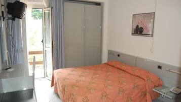 Una camera da letto con un letto, un comodino con il telefono, uno specchio, un armadio e una televisione.