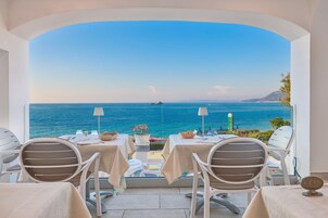 Una terraza con mesas y sillas con vista al mar.