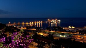 A coastal cityscape at night with illuminated buildings, a bridge, and a marina. - Hotel Ideale (Ortona)