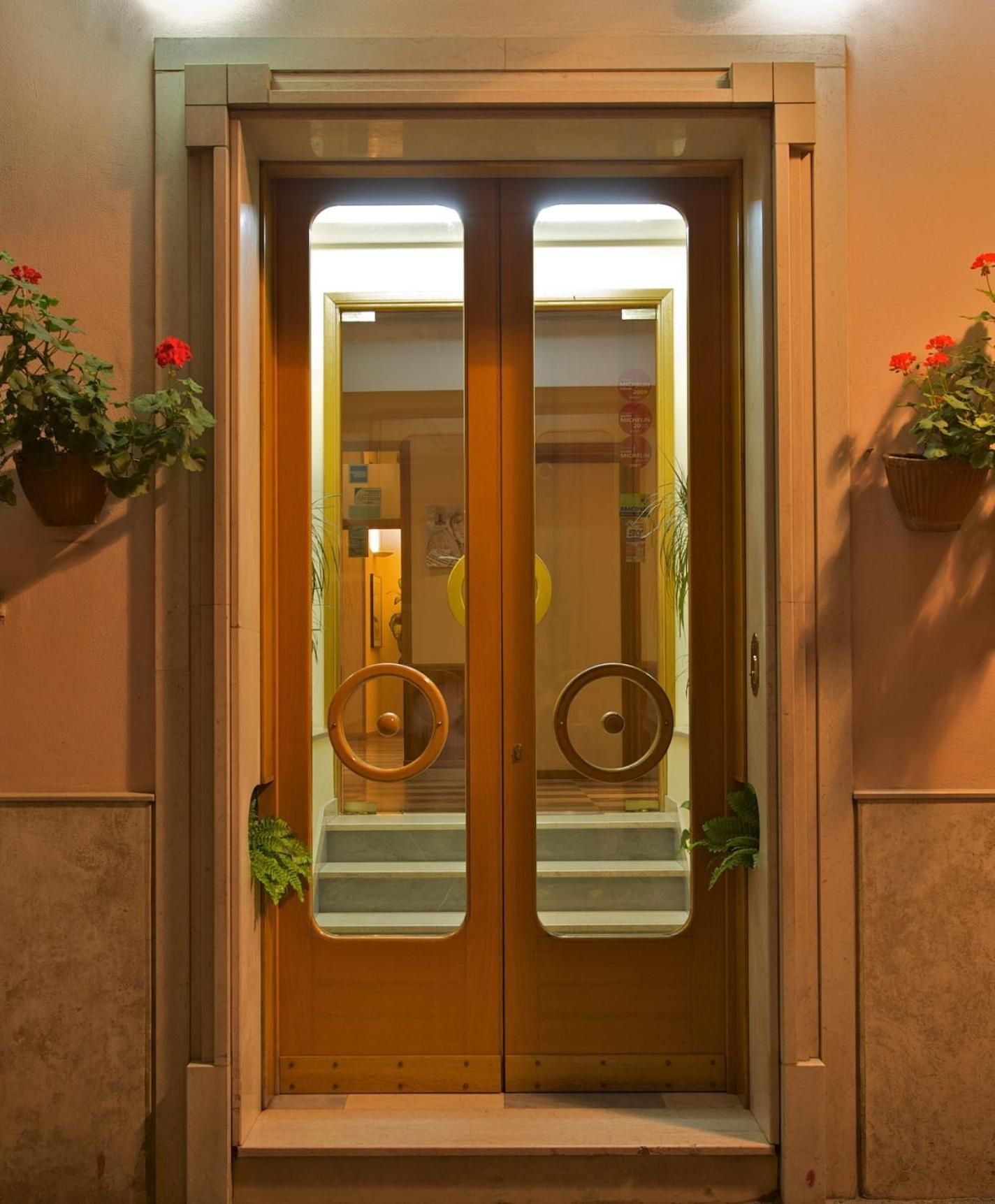 Una doppia porta con pannello in vetro, cornice in legno e un piccolo gradino che conduce all'ingresso.