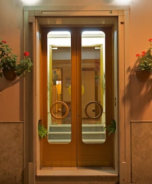 A double door with a glass panel, a wooden frame, and a small step leading up to the entrance. - Hotel Ideale (Ortona)