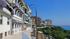 A coastal promenade with a curved pathway, balconies with flower boxes, and a view of the sea. - Hotel Ideale (Ortona)