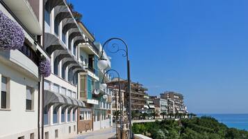 Una passeggiata costiera con un percorso curvo, balconi fioriti e vista sul mare.