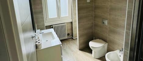 Un baño moderno con ducha, inodoro, bidé y lavamanos.