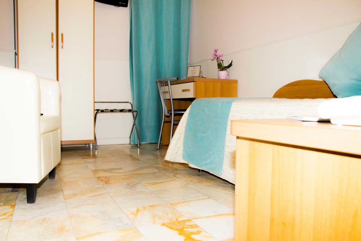 Habitación de hotel con cama, escritorio, silla, armario y baño.
